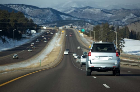 Cars driving on a mountainous highway with snow on the ground