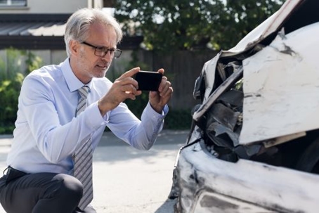 man taking picture of car damage